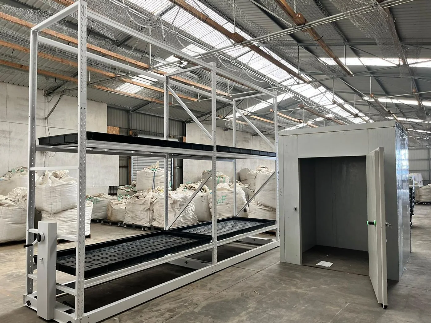 White two-tier rolling vertical rack beside a grow room
